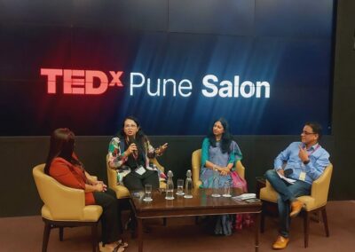 People around a table with a TEDx Pune Salon sign behind them